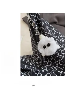 Gros plan d'un charme monstre en peluche blanche avec de grands yeux sur sac noir et blanc
