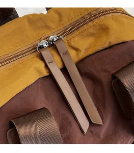 Detail of smooth double metal zippers with leather pulls on waterproof nylon backpack