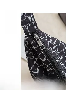 Gros plan d'une fermeture éclair en métal argenté sur un sac en toile à motif noir et blanc