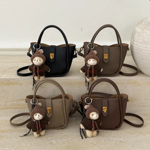 Close-up of litchi grain leather handbags with teddy bear charms on stone steps