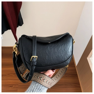 Détail du sac demi-lune en similicuir noir avec texture grainée et boucles dorées