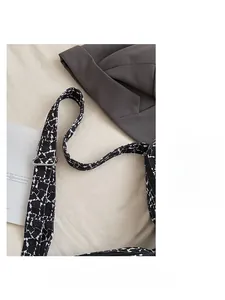Détail de la bandoulière réglable en textile avec motif noir et blanc du sac seau