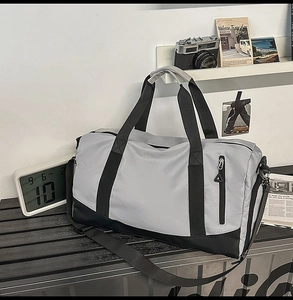 Grey and black gym bag with waterproof zipper and shoulder strap on a wooden bench