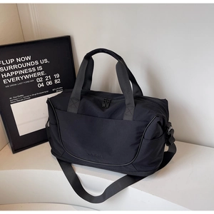 Detail view of black waterproof nylon duffel bag with branded embossed logo on white steps