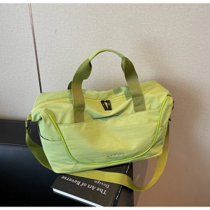 Neon green travel duffel bag with dual handles and shoulder strap on a black chair