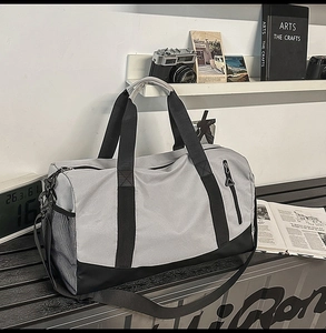 Detail of grey oxford sports bag with reinforced handles and side mesh pocket on bench