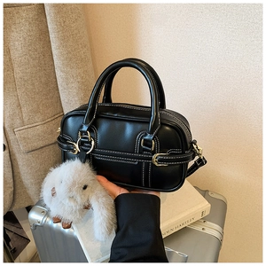 Detail of black leather Boston bag with white stitching and gold hardware detail