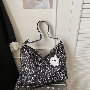 Vue détaillée du grand sac cabas floral avec charm en peluche sur valise argentée