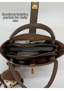 Vue détaillée de l'intérieur spacieux d'un sac seau en cuir marron avec un petit ours décoratif