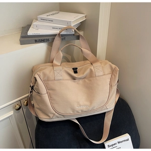 Detail of beige large travel bag with adjustable strap on a chair