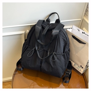 Close-up of black water-resistant nylon backpack with drawstring pockets on a table