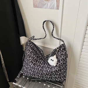 Détail du sac cabas floral avec fermeture éclair et breloque peluche sur valise