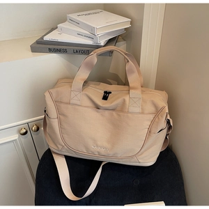 Detail of beige large travel bag with durable handles and adjustable shoulder strap