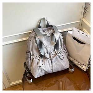 Detail of grey-purple waterproof nylon backpack with wide straps and side drawstring pocket