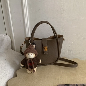 Detail of dark brown lychee grain leather handbag with cute teddy bear bag charm accessory