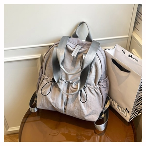 Detailed close-up of grey waterproof nylon backpack showing gathered fabric and side pocket