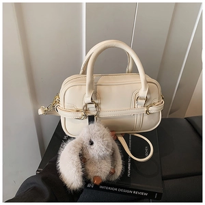 Detail view of beige crossbody pillow bag with metal ring and cute rabbit charm