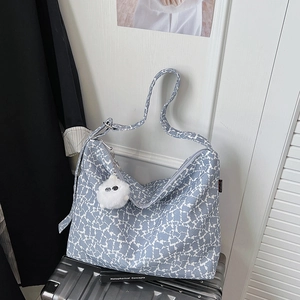Détail du sac cabas à motifs abstraits bleu et blanc avec un joli pendentif chat