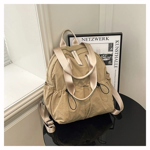Detailed view of water-resistant beige nylon backpack with drawstring side pockets
