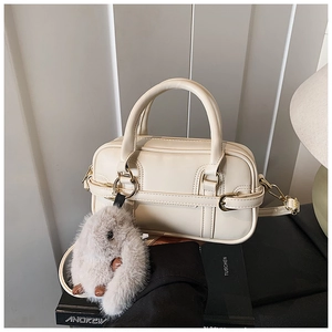 Detail of cream pillow bag with structured stitching, top handles and plush bunny charm