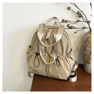 Close-up of khaki waterproof nylon backpack on a wooden table with ceramic vase decor