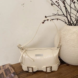 Retro cream faux leather underarm bag with silver buckles on a wooden table