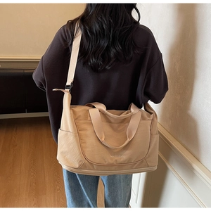 Close-up of khaki travel bag with wide shoulder strap and separate bottom shoe compartment