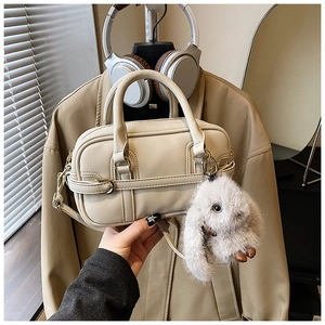 Detailed view of beige pillow bag with leather texture and cute white bunny charm