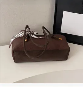 Détail du sac cabas tissé marron avec foulard en soie et finitions en métal doré