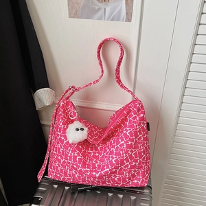 Détail du sac hobo à fleurs rose rouge avec charme en peluche blanche sur valise argent