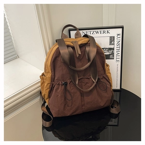 Detail of multi-pocket nylon backpack showing brown color-blocking and drawstring front pouches