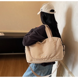 Detail of beige travel bag with wellalbag logo, wide handles and adjustable strap