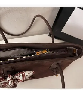 Détail d'un sac cabas en cuir tressé marron avec fermeture éclair et foulard en soie imprimé