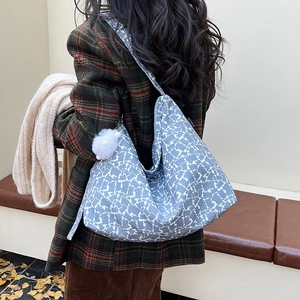 Détail du sac hobo en toile bleu et blanc avec breloque peluche sur manteau à carreaux