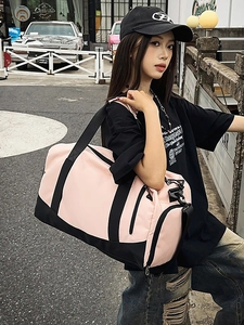 Pink and black sports gym bag with shoe compartment shown on female model in street setting