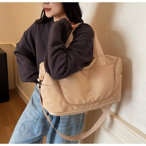 Close-up of beige canvas duffel bag with shoulder strap and Weilailbag embroidery details