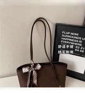 Détail d'un sac cabas marron foncé à texture tissée et nœud décoratif en foulard de soie