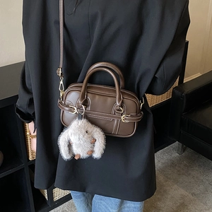 Detail of brown faux leather Boston bag with contrast stitching and cute rabbit charm