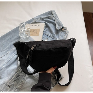 Détail du sac de poitrine en toile noire avec tirette tressée et sangle à boucle
