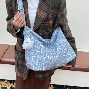 Détail du sac cabas à fleurs bleues avec pendentif peluche sur un fond d'automne