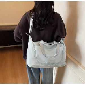 Detail of mint green travel bag featuring a bottom shoe compartment and adjustable strap
