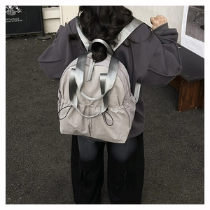 Detail of grey water-resistant nylon backpack with glossy silver straps and drawstring