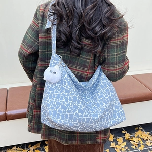 Vue détaillée du dos d'un sac cabas bleu à fleurs avec un charme pompon blanc en peluche