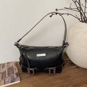 Detail of vintage black underarm bag with silver buckles and studs on wooden table