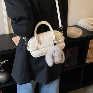 Model view of cream pillow bag with plush bunny charm and adjustable crossbody strap
