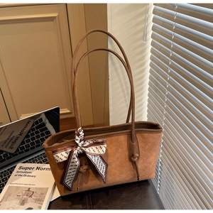 Détail du cabas en daim marron avec motif matelassé et foulard en soie décoratif