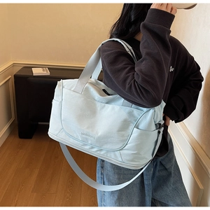 Light blue large travel duffel bag with shoulder strap shown in lifestyle use