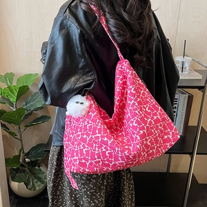 Détail d'un grand sac cabas en toile rose à fleurs avec un pendentif en peluche blanc