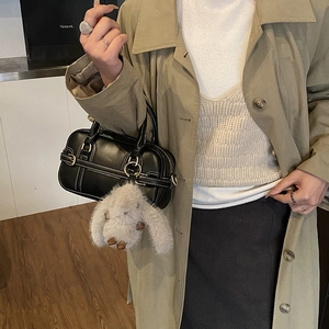 Detail view of black leather pillow bag with white stitching and rabbit charm