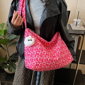 Détail du sac hobo en toile fleurie rose avec breloque boule de peluche blanche tendance